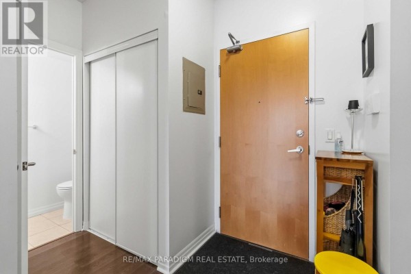 Apartment interior with a closed sliding closet door and a wooden door. - 2503 - 3939 Duke Of York Boulevard, Mississauga