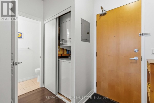 Apartment entrance with a closet containing a stacked washer and dryer. - 2503 - 3939 Duke Of York Boulevard, Mississauga