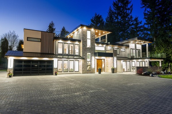 Attached three-car garage with black doors and vertical lighting on a paved driveway. - 25031 57 Avenue, Langley
