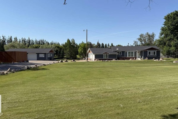 View of the front of a home and detached garage with a large green lawn. - 25032 Richfield Rd, Rural Sturgeon County