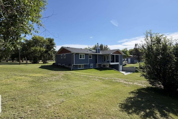 Side and rear view of the dark blue home with a walk-out basement on a lawn. - 25032 Richfield Rd, Rural Sturgeon County