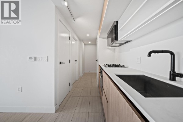 Open concept kitchen and dining area with light wood cabinets, stainless steel appliances, and tiled floors. - 2504 5058 Joyce Street, Vancouver