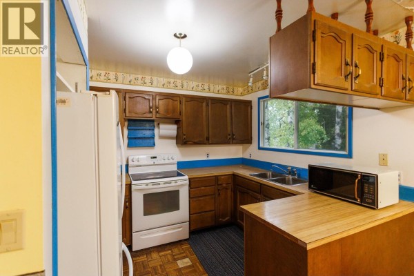Kitchen with wood cabinets, white stove, and stainless steel sink. - 2504 Kerr Street, Terrace