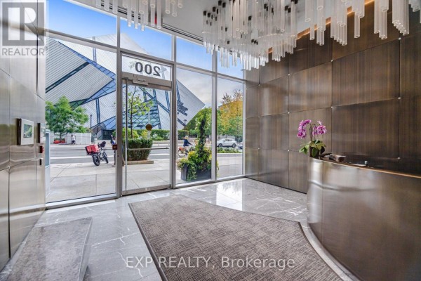 Luxury condo lobby with glass entrance, marble floors, and metallic wall panels. - 2505 - 200 Bloor Street W, Toronto