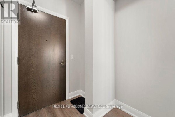 Apartment entrance door with dark wood finish and a small black doormat. - 2505 - 2900 Hwy 7, Vaughan
