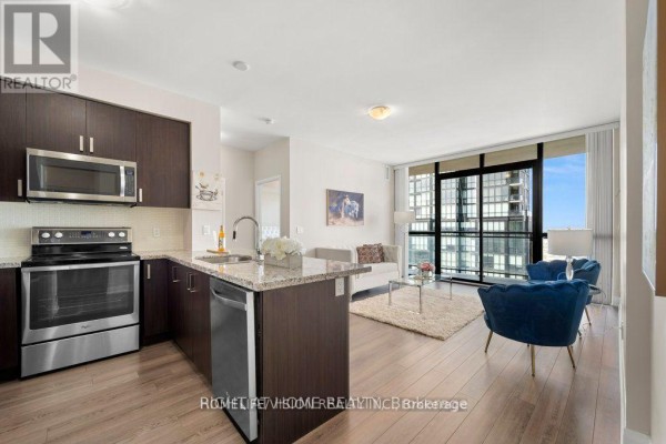 Open concept living area with a modern kitchen, sofa, and floor-to-ceiling windows. - 2505 - 2900 Hwy 7, Vaughan