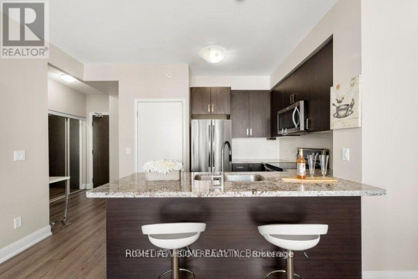 Kitchen island with granite countertop, sink, faucet, and two white bar stools. - 2505 - 2900 Hwy 7, Vaughan