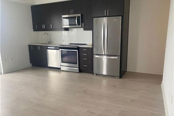 A modern kitchen with dark cabinets, stainless steel appliances, and light wood flooring. - 2506 - 8 Nahani Way, Mississauga