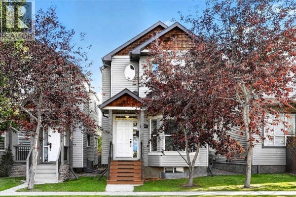 Front exterior of a light grey home with a gabled roof and wood accents. - 2506 17 Street Se, Calgary