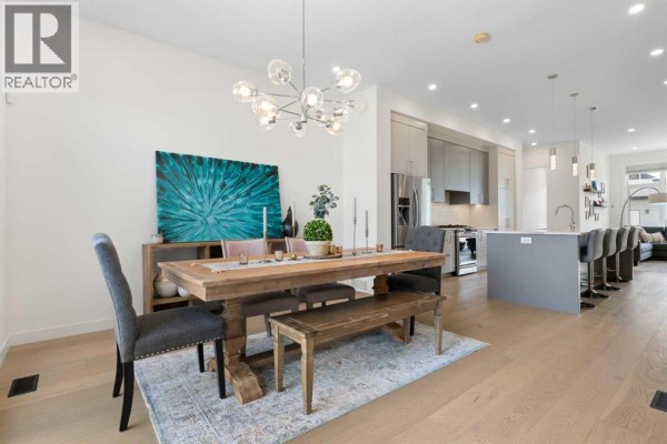 Dining room with a wooden table, chairs, bench, and large windows. - 2507 17 Street Nw, Calgary