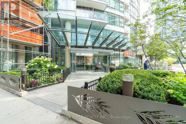 Exterior view of building entrance with walkway, landscaping, and metal fencing. - 2509 - 373 Front Street W, Toronto