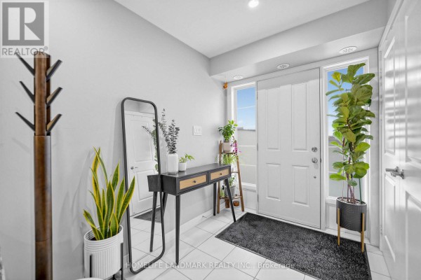 Interior foyer with white walls, tiled floor, and white doors, featuring a console table and plants. - 251 - 60 Parrotta Drive, Toronto
