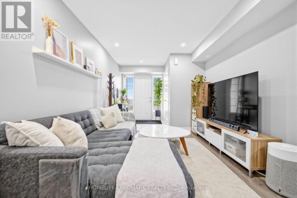Living room with grey sectional sofa, white coffee table, and television on a media stand. - 251 - 60 Parrotta Drive, Toronto