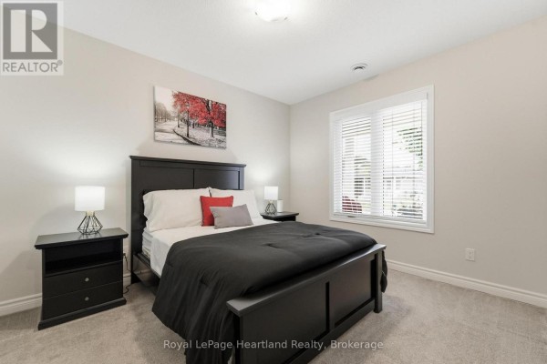 A bedroom with a king-size bed, black furniture, grey carpet, and a large window. - 251 Lake Breeze Drive, Ashfield Colborne Wawanosh