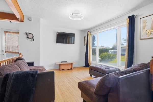Living room with hardwood floors, white walls, and a large bay window with view of the backyard. - 251 Rue Marquette, Gatineau