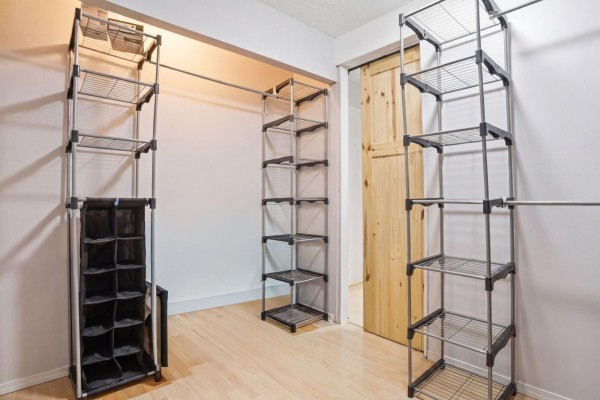 Walk-in closet with metal shelving units, shoe organizer, and a wooden sliding door. - 251 Rue Marquette, Gatineau