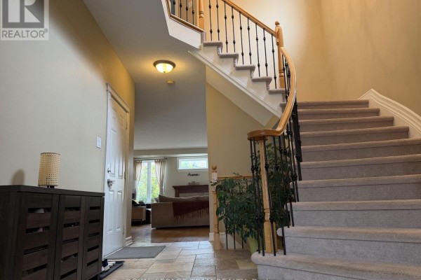 Foyer with a tiled floor, staircase with carpeted steps and a wooden banister. - 251 Tofino Private, Ottawa
