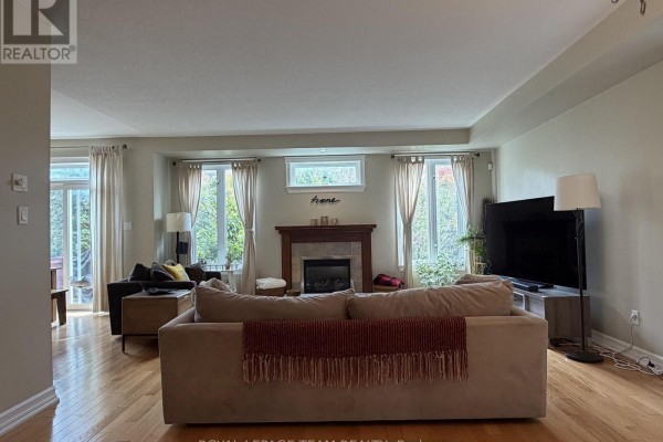 Living room with hardwood floors, a fireplace, large windows, and a sectional sofa. - 251 Tofino Private, Ottawa