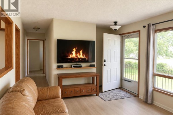 Living room with a leather couch, fireplace on TV, and front door. - 2510 35 Street Se, Calgary