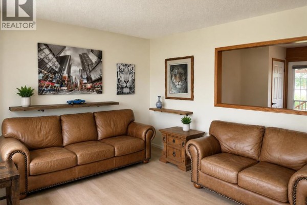 Living room with two brown leather couches, wood shelves, and wall art. - 2510 35 Street Se, Calgary