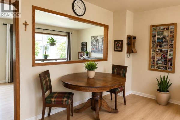 Dining area with a round wood table, two chairs, and a mirror on the wall. - 2510 35 Street Se, Calgary