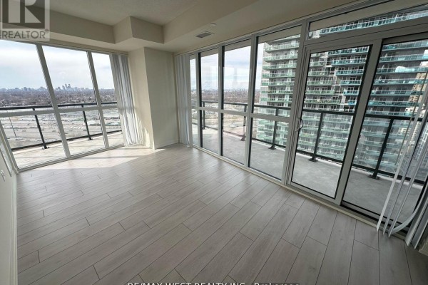 Empty living room with light wood laminate flooring and large windows overlooking city skyline. - 2511 - 38 Annie Craig Drive, Toronto