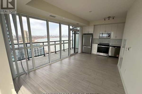 Open-concept living and kitchen area with floor-to-ceiling windows and Toronto skyline view. - 2511 - 38 Annie Craig Drive, Toronto