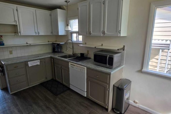 Kitchen with white and grey cabinets, granite countertops, stainless steel appliances, and a window. - 2515 Cochrane Road Nw, Calgary