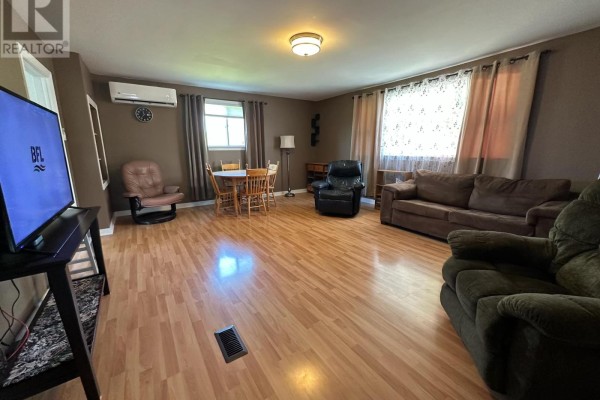 Living room with wood-look flooring, brown walls, couches, chairs, and a dining set. - 2515 Highway 2, Shubenacadie