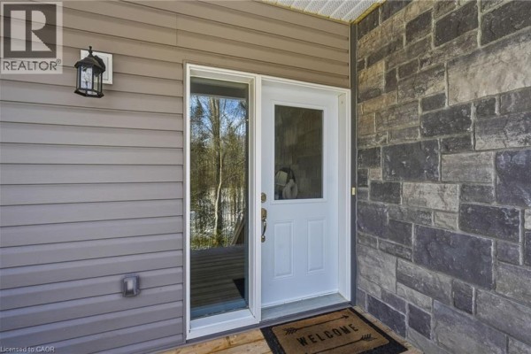 Close-up of the front door with a welcome mat and stone accents - 2516 Irish Line, Coldwater