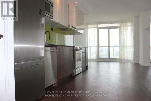 Open concept living area with a modern kitchen and large windows showing city views. - 2517 - 121 Mcmahon Drive, Toronto