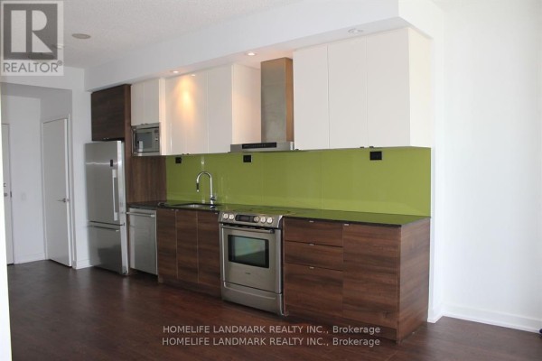 Modern kitchen with stainless steel appliances, dark wood cabinets, and a green glass backsplash. - 2517 - 121 Mcmahon Drive, Toronto