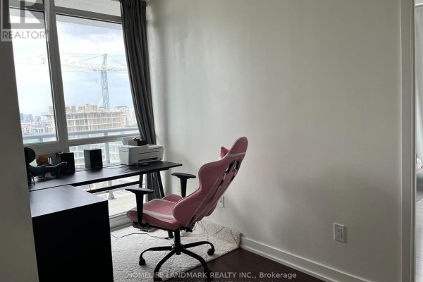 Home office setup with a desk, pink ergonomic chair, and window overlooking city construction. - 2517 - 121 Mcmahon Drive, Toronto