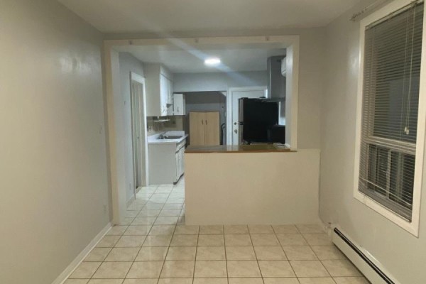 View from dining area to kitchen through a half-wall opening with white cabinets. - 2518 Lake Shore Boulevard, Toronto
