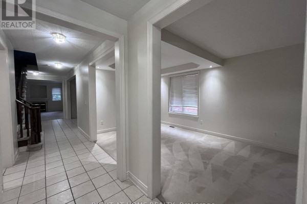 Interior hallway with tile flooring, doorways to rooms, and view of stairs. - 2518 Rugby Road, Mississauga