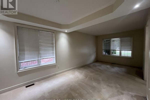 Spacious living room with carpet, two windows, and neutral-colored walls. - 2518 Rugby Road, Mississauga