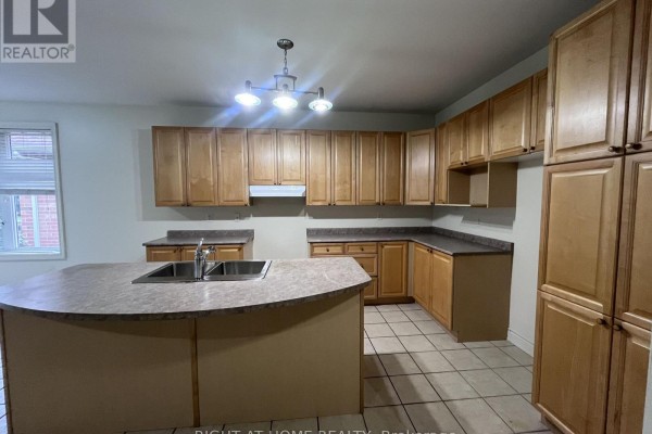 Kitchen with light wood cabinets, tiled floor, and an island with a sink. - 2518 Rugby Road, Mississauga