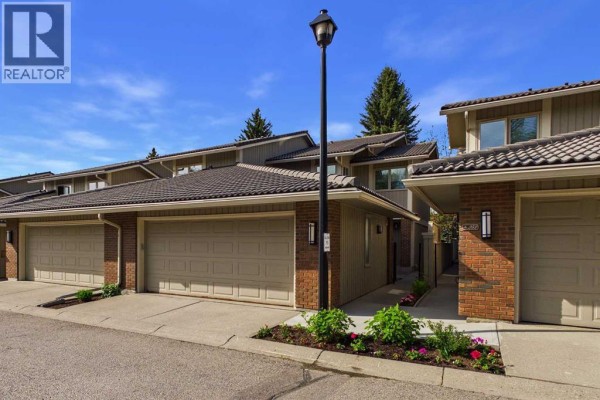 Front exterior of duplex homes with attached garages and landscaped gardens. - 252, 20 Midpark Crescent Se, Calgary