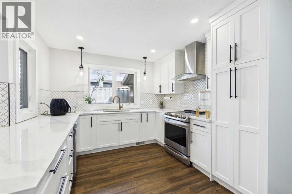 White kitchen with stainless steel appliances, subway tile backsplash, and ample cabinetry. - 252, 20 Midpark Crescent Se, Calgary