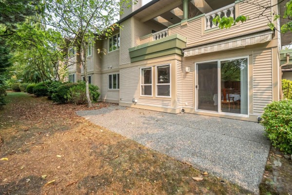 Back of townhouse with patio, sliding glass door, and grassy area. - 252 13888 70 Avenue, Surrey