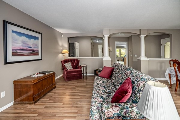 Living room with decorative columns, furniture, and view into hallway. - 252 13888 70 Avenue, Surrey