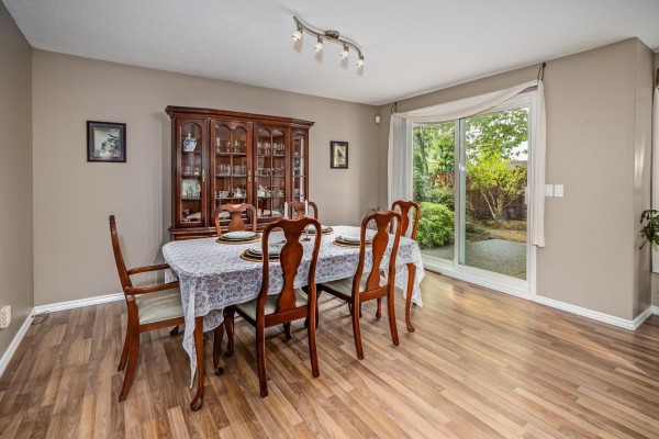 Dining room with wood hutch, table set for six, and patio door. - 252 13888 70 Avenue, Surrey