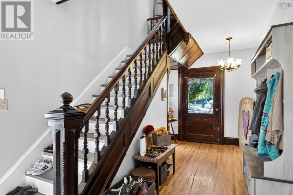 Interior entryway with dark wood staircase, hardwood floors, a wooden bench, and a chandelier. - 252 Main Street, Berwick