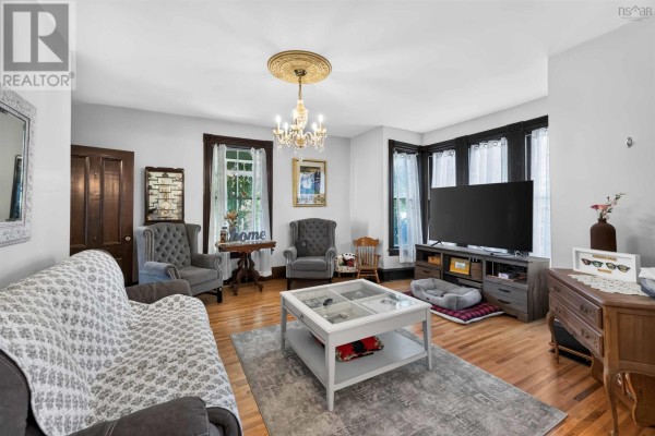 Living room with gray sofas, armchair, coffee table, TV, hardwood floors, and ornate ceiling medallion. - 252 Main Street, Berwick