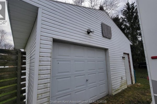 White garage with siding, garage door, and wooden fence - 252 Queen Street Highgate