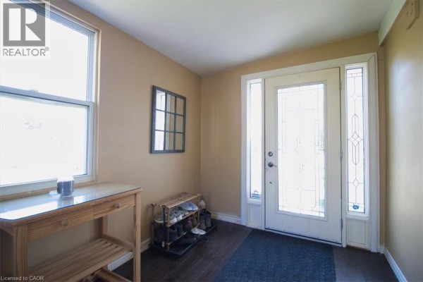Living area with a striped sofa, small wooden table with shelves, and a window overlooking an RV. - 252 Queen Street, Highgate
