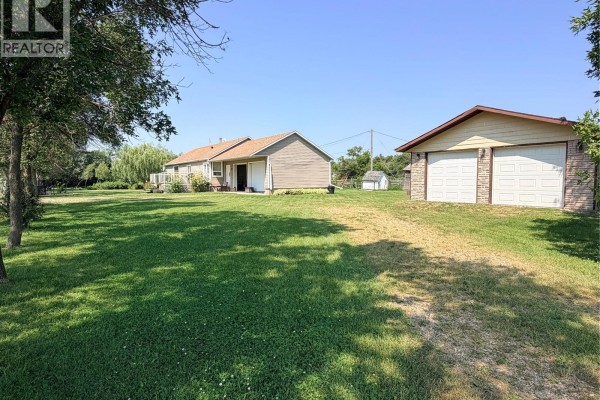 View of the side of the house and detached garage with a large grassy yard. - 252 Railway Avenue, Forget