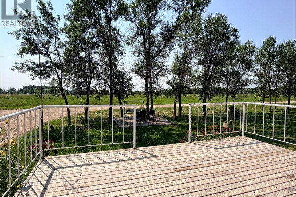 Wooden deck with white railings offering a view of trees and open fields. - 252 Railway Avenue, Forget