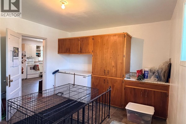 Interior room with two chest freezers, wooden cabinets, and a view into a white kitchen. - 252 Railway Avenue, Forget