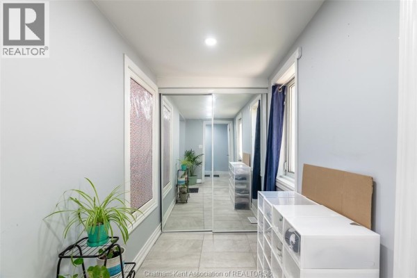 Hallway with light blue walls, tiled floor, and mirrored closet doors reflecting the space. - 252 Wellington Street East, Chatham